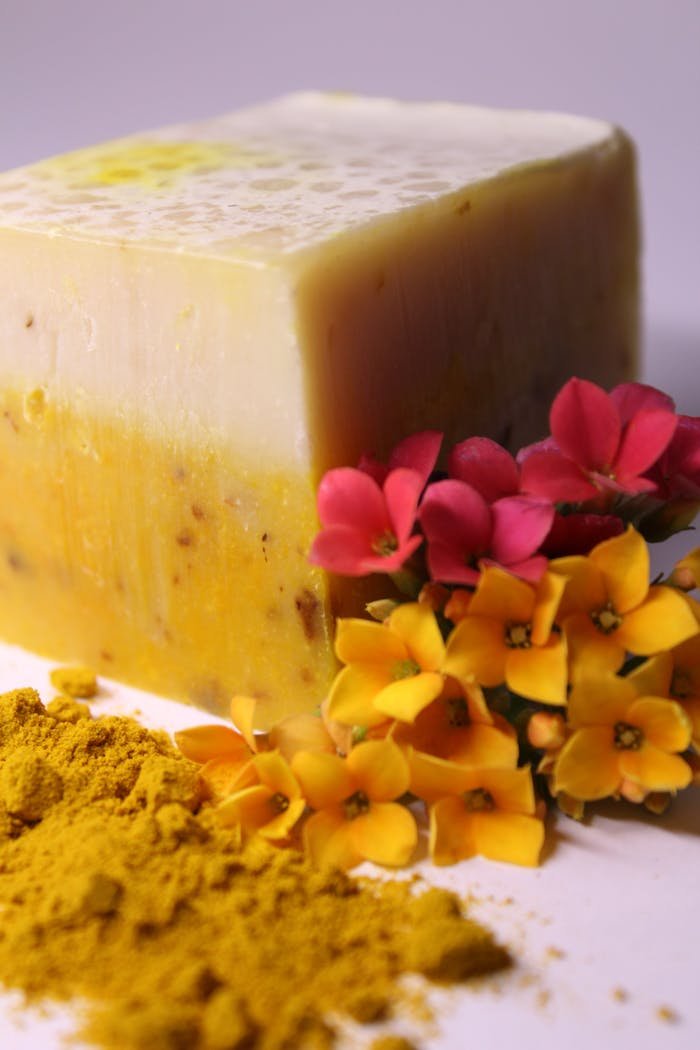Natural turmeric soap close-up with colorful flowers and powder. Ideal for skincare concepts.